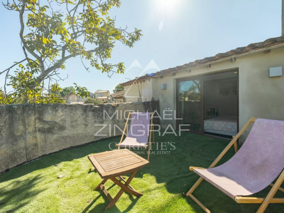 Terrasse d'une maison provençale avec chaise longue et table, entourée de murs en pierre.