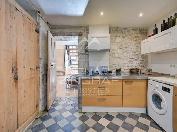 Cuisine d'un appartement dans un hôtel particulier du XVIIème siècle à Avignon, avec murs en pierre et carrelage.