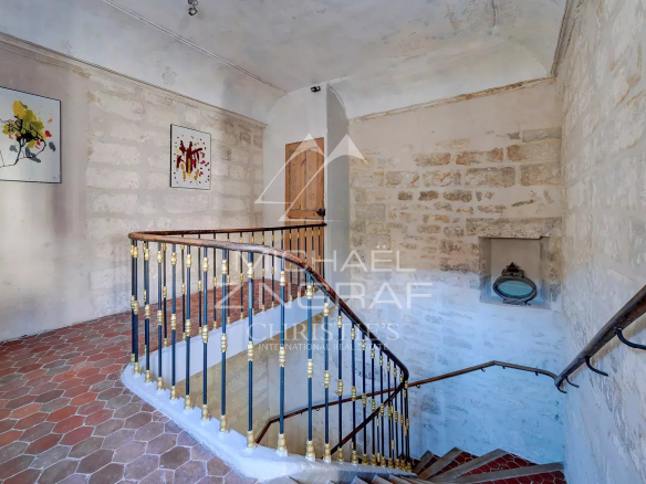 Escalier en colimaçon dans un hôtel particulier du XVIIème siècle à Avignon, avec murs en pierre et œuvres d'art.