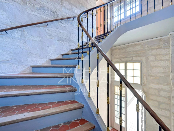 Escalier en colimaçon dans un hôtel particulier du XVIIème siècle à Avignon, avec murs en pierre et balustrade en fer forgé.