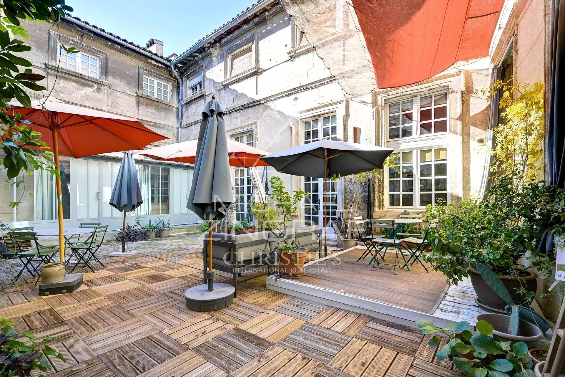 Terrasse d’un hôtel particulier à Avignon Terrasse ensoleillée d'un hôtel particulier du XVIIème siècle à Avignon, avec parasols et mobilier de jardin.