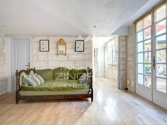 Intérieur d'un appartement rénové avec un canapé et des murs en pierre, lumière naturelle
