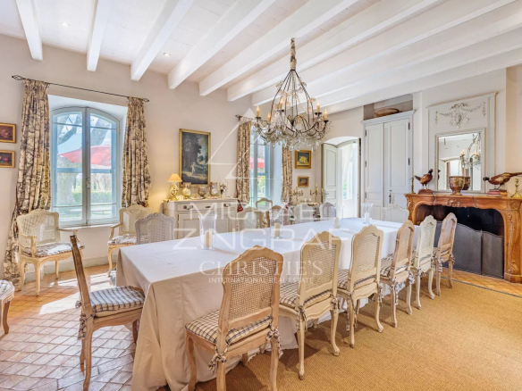 Dining room of a Provençal property with a large table and wicker chairs.