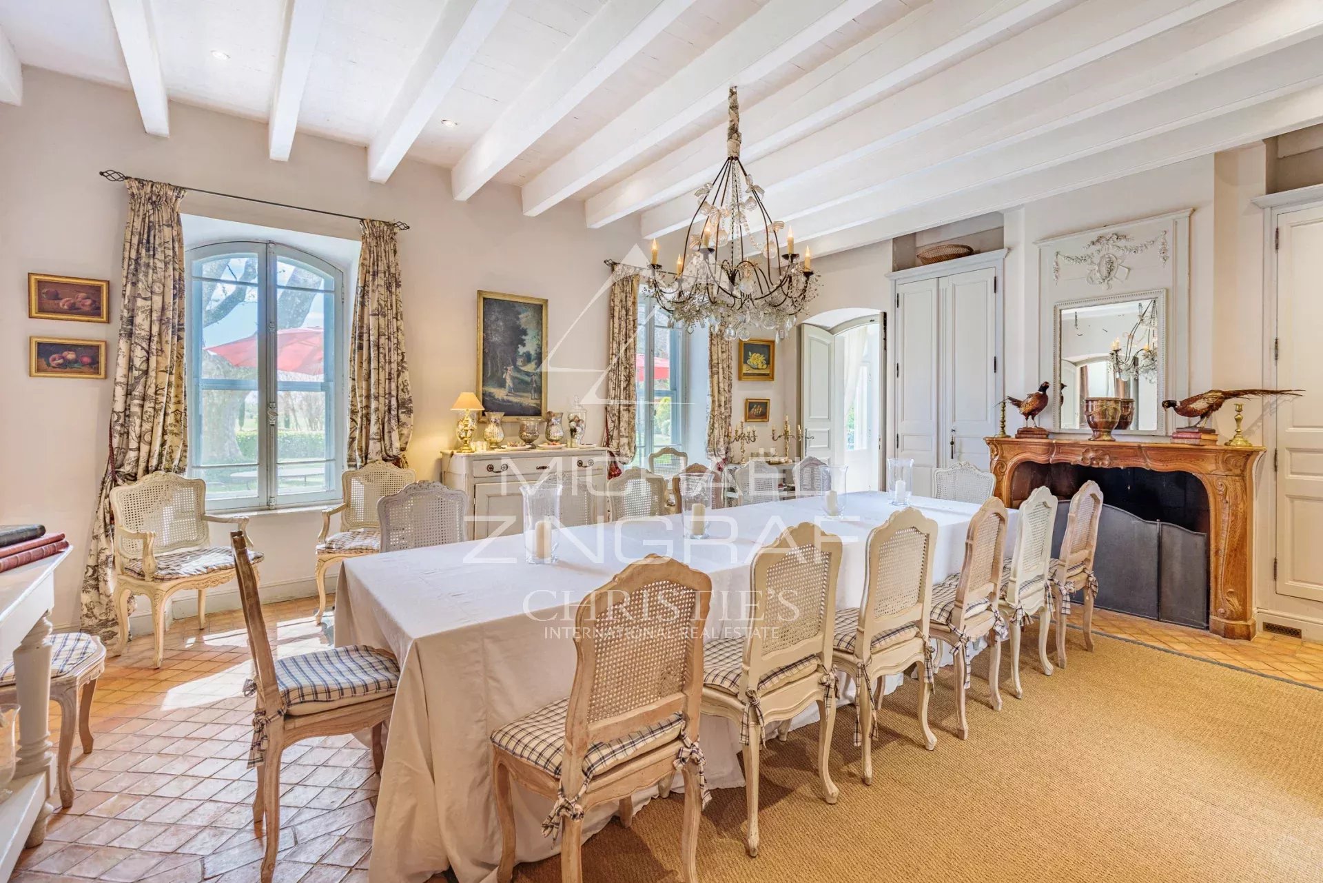 Dining room of a Provençal property with a large table and wicker chairs.