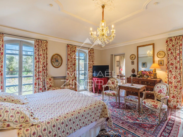 Spacious room with four-poster bed and Provençal decor, windows overlooking the garden.