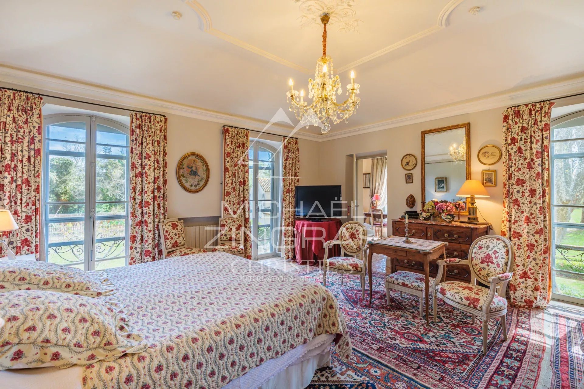 Spacious room with four-poster bed and Provençal decor, windows overlooking the garden.
