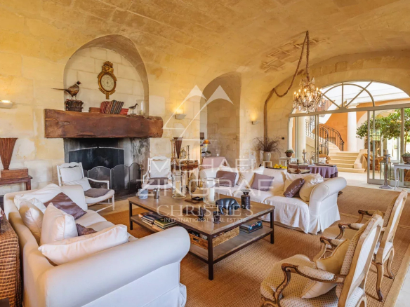 Interior of a Provençal farmhouse with a bright living room and stone fireplace.