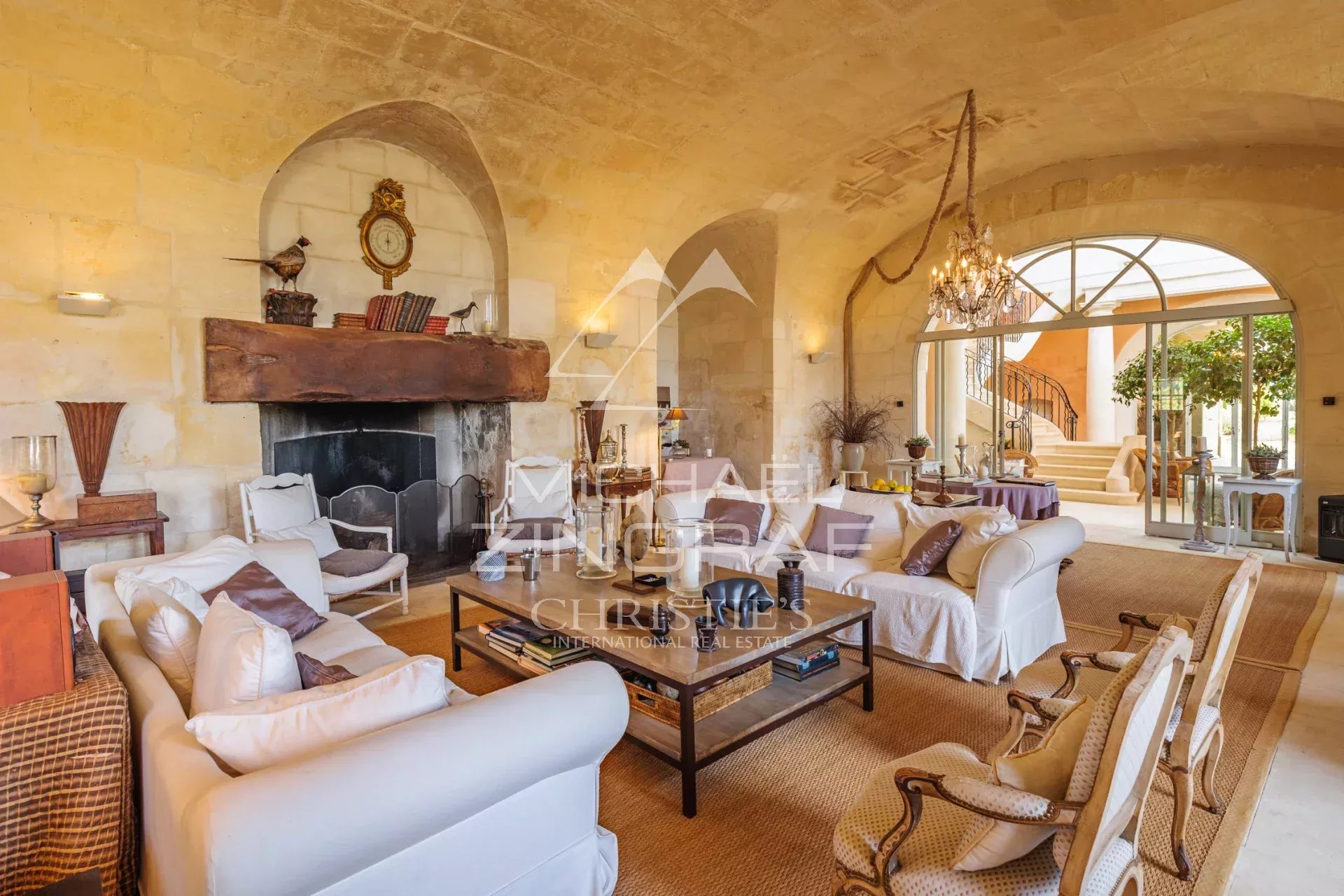 Interior of a Provençal farmhouse with a bright living room and stone fireplace.