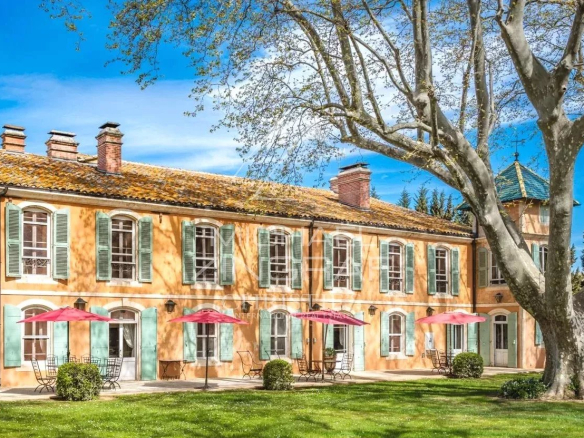 Provençal property with a colorful facade and parasols in the garden.