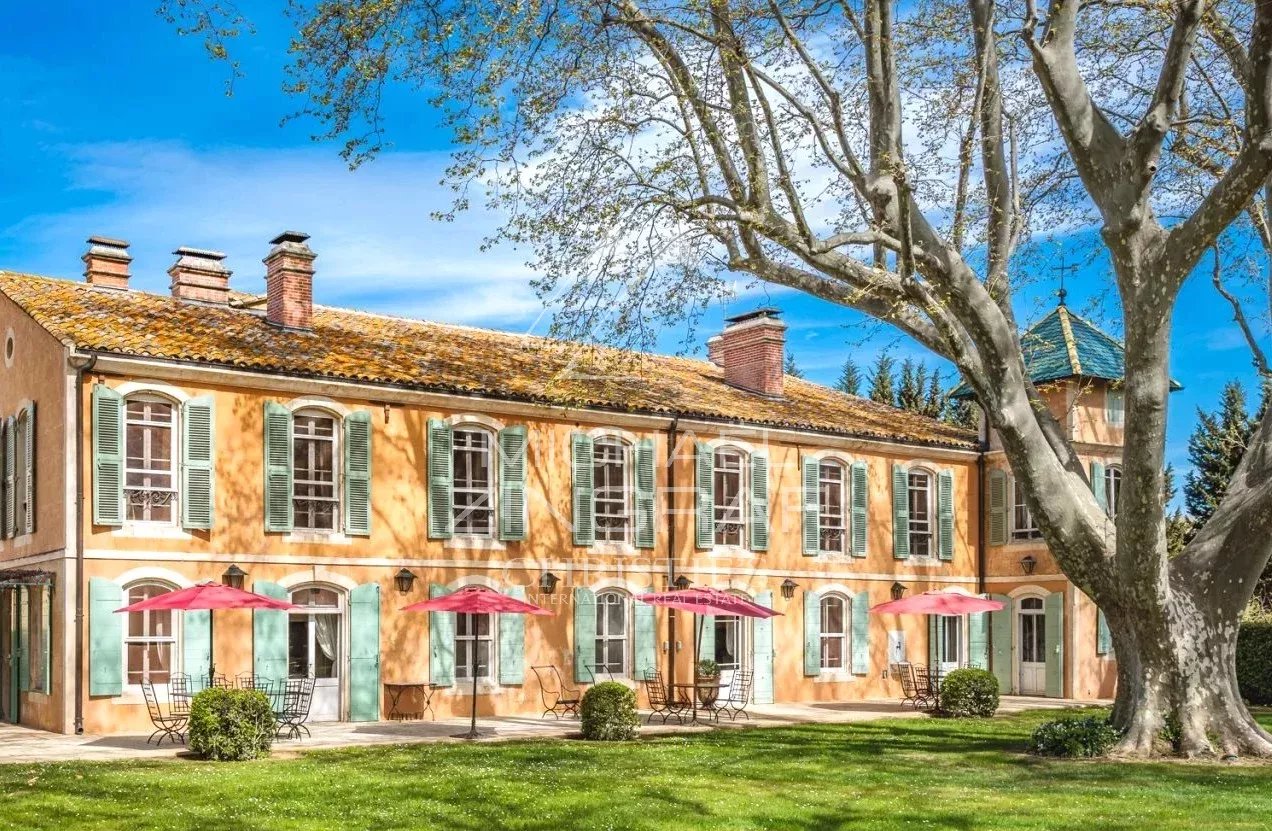 Provençal property with a colorful facade and parasols in the garden.