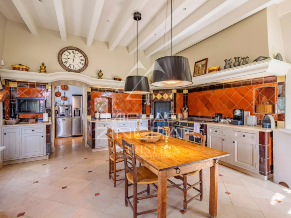 Spacious kitchen with wooden table and colorful tiles in a Provençal property.