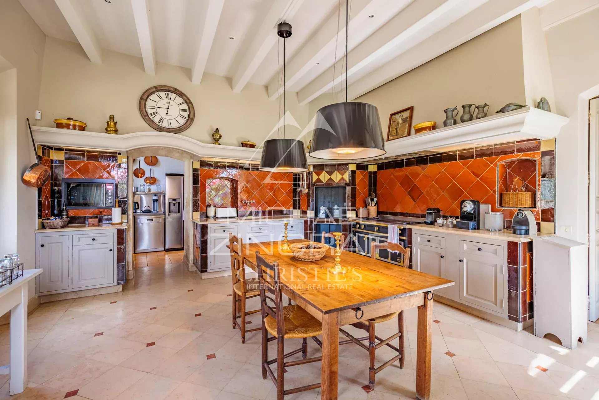 Spacious kitchen with wooden table and colorful tiles in a Provençal property.