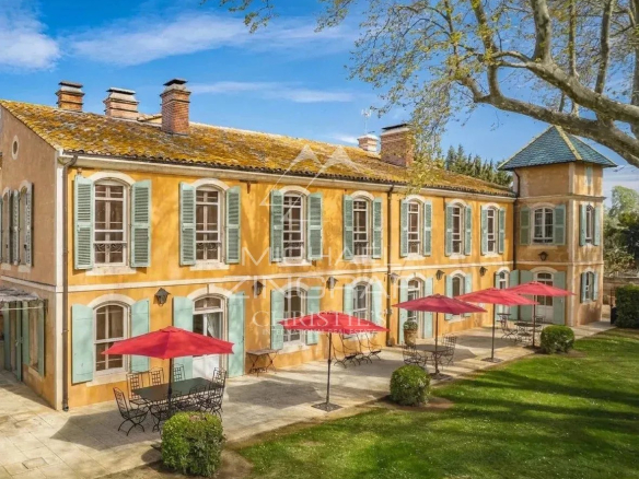 Propriété avec façade en pierre et volets verts, entourée de verdure à Arles.
