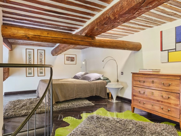 Chambre d'un appartement rénové avec poutres apparentes et mobilier contemporain à Aix-en-Provence.