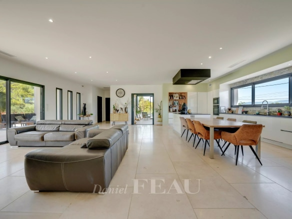 Intérieur d'une propriété contemporaine avec salon et cuisine ouverte, baignée de lumière.