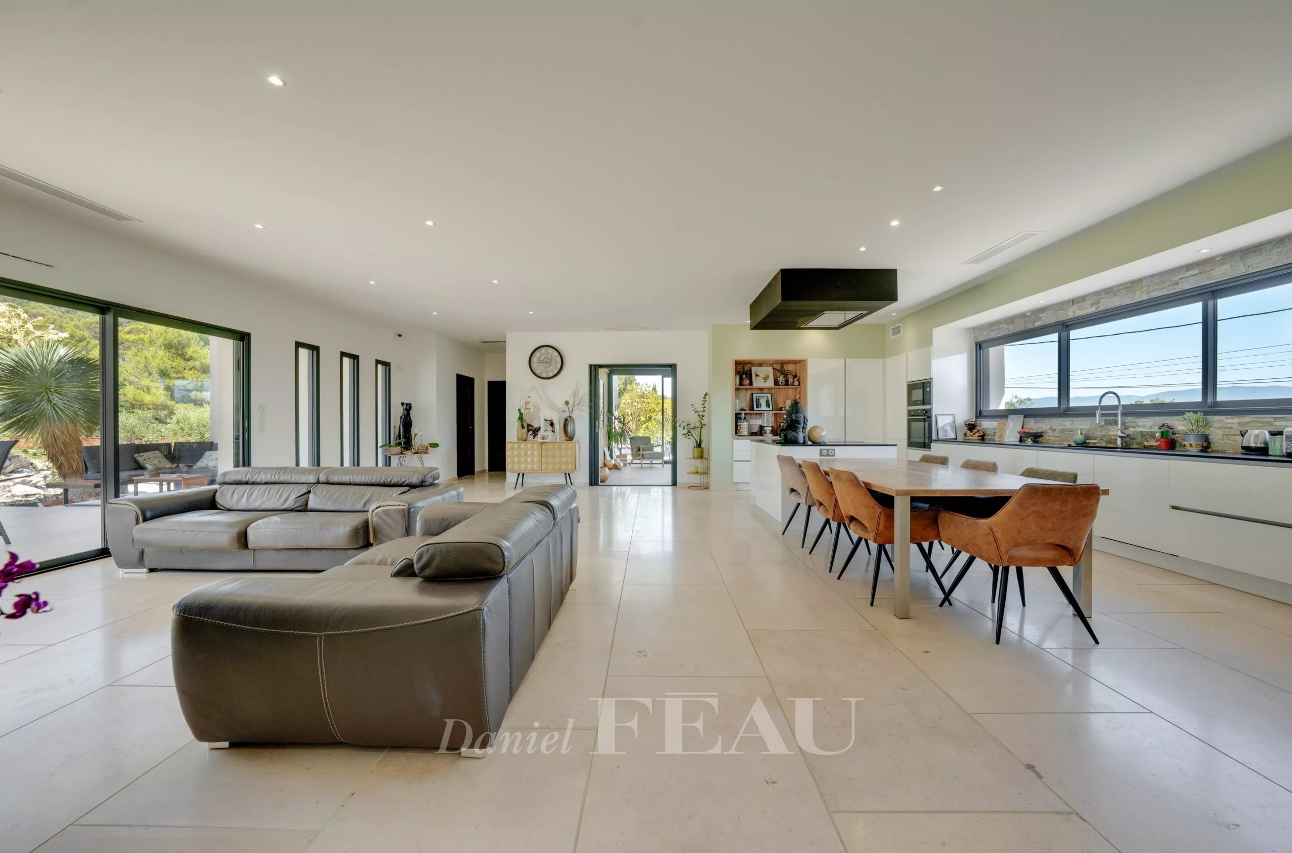 Intérieur d'une propriété contemporaine avec salon et cuisine ouverte, baignée de lumière.