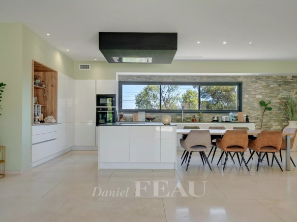 Cuisine moderne et lumineuse avec table à manger et grandes fenêtres, dans une propriété contemporaine.