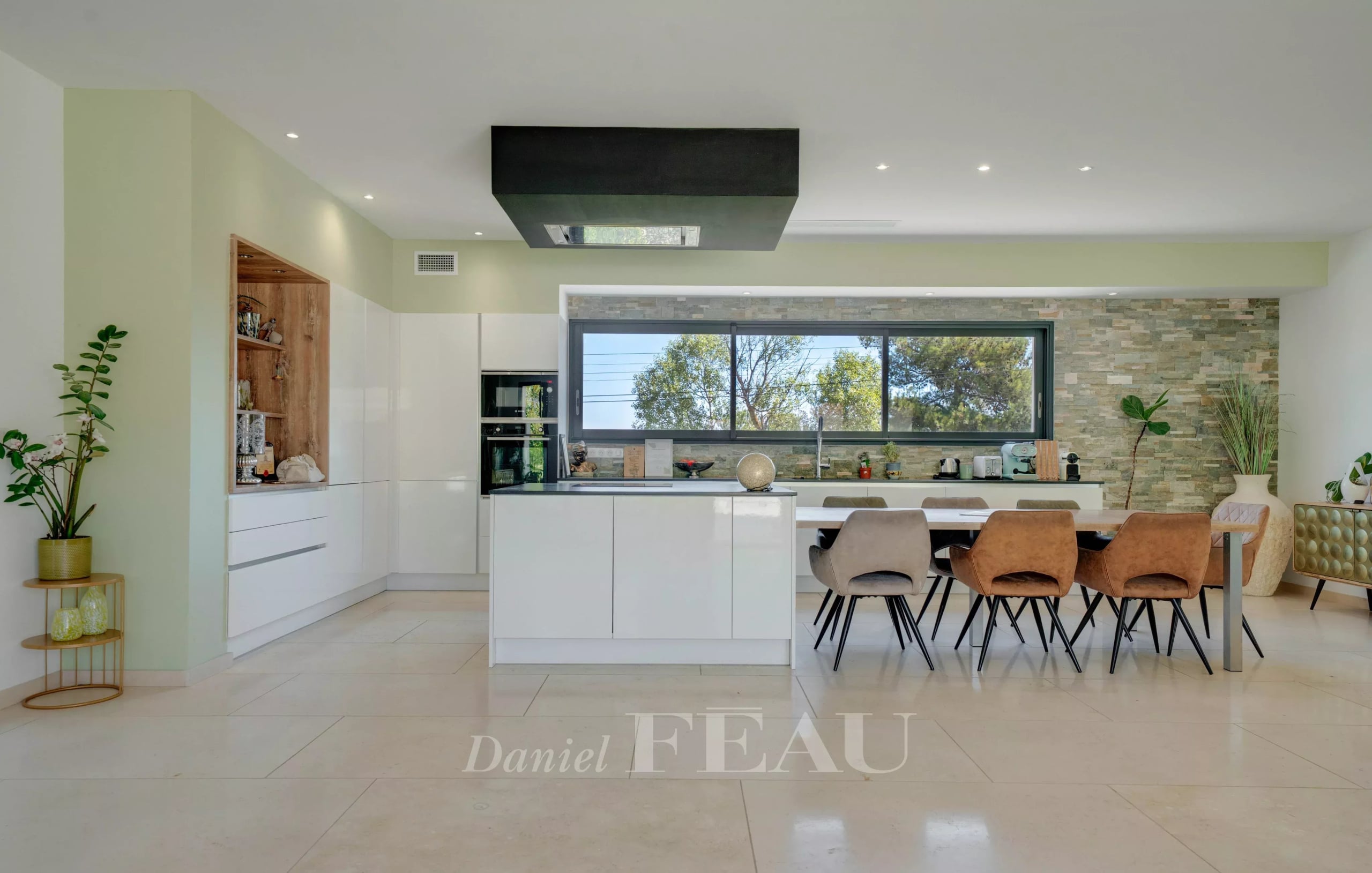 Cuisine moderne et lumineuse avec table à manger et grandes fenêtres, dans une propriété contemporaine.