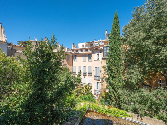 Vue d'un immeuble avec jardin à Aix-en-Provence, ciel bleu et arbres en arrière-plan.