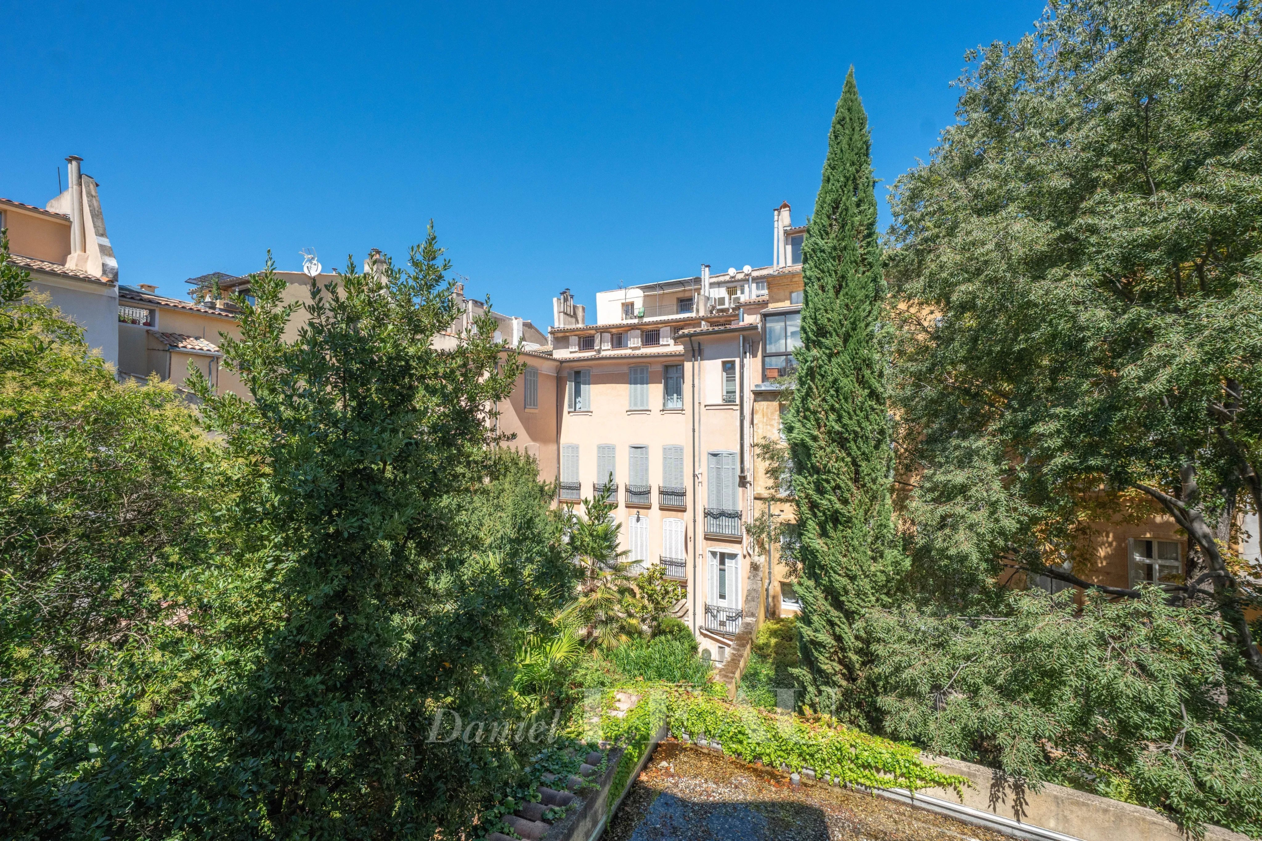 Immeuble à Aix-en-Provence Vue d'un immeuble avec jardin à Aix-en-Provence, ciel bleu et arbres en arrière-plan.