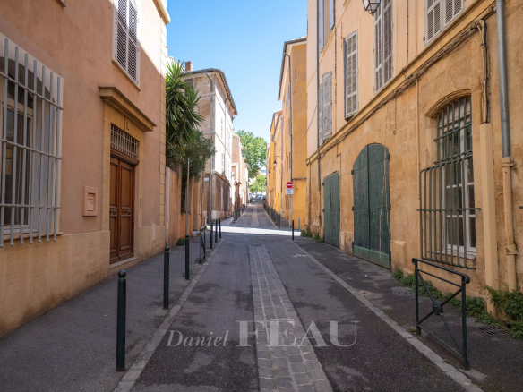 Rue calme du centre historique d'Aix-en-Provence, avec bâtiments en pierre et végétation.