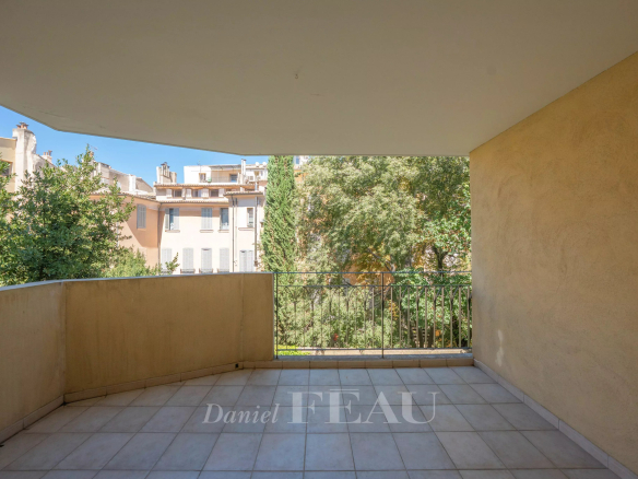 Terrasse d'un appartement à Aix-en-Provence avec vue sur des arbres et bâtiments voisins.