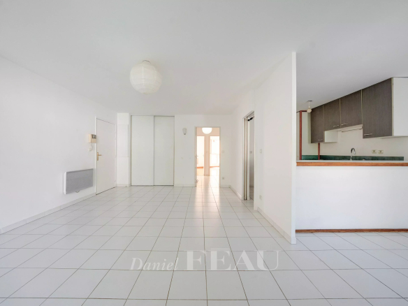 Intérieur d'un appartement vide avec carrelage blanc, cuisine ouverte et lumière naturelle à Aix-en-Provence.