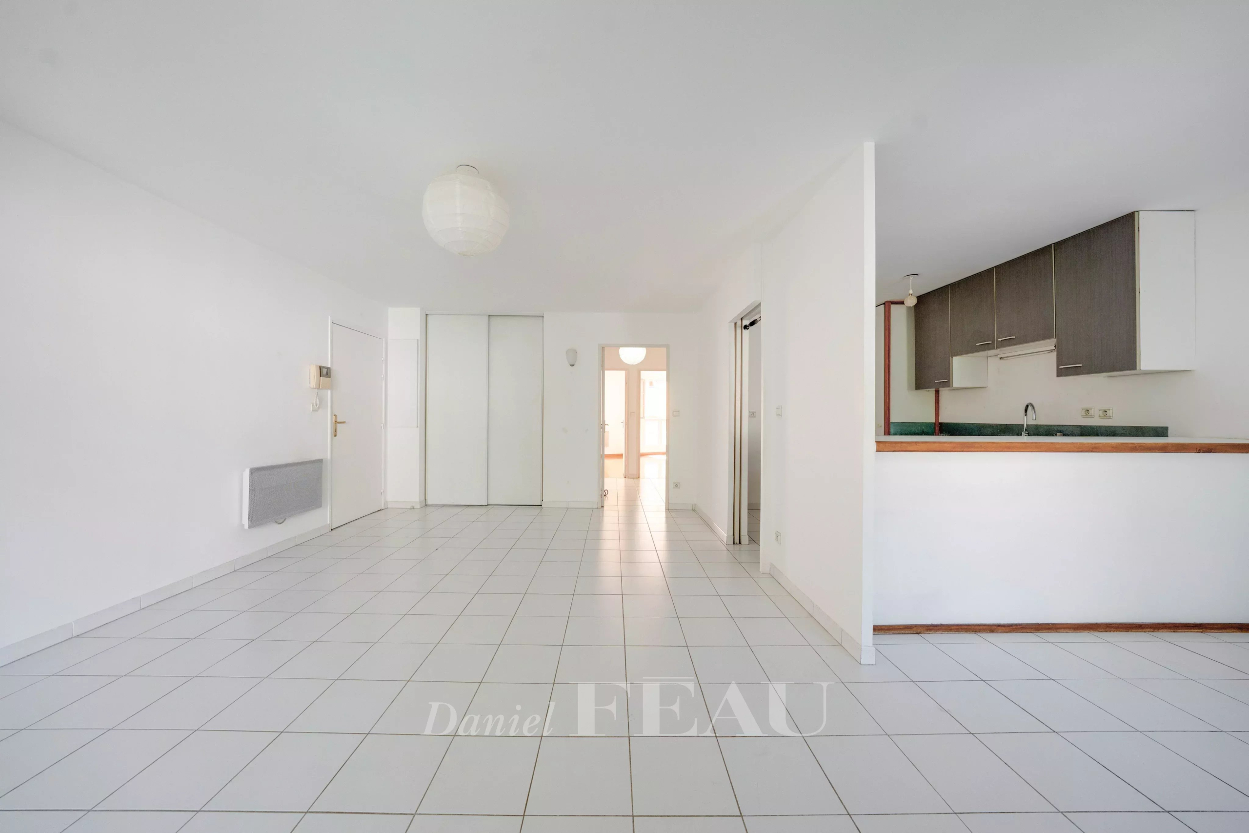Appartement à Aix-en-Provence Intérieur d'un appartement vide avec carrelage blanc, cuisine ouverte et lumière naturelle à Aix-en-Provence.