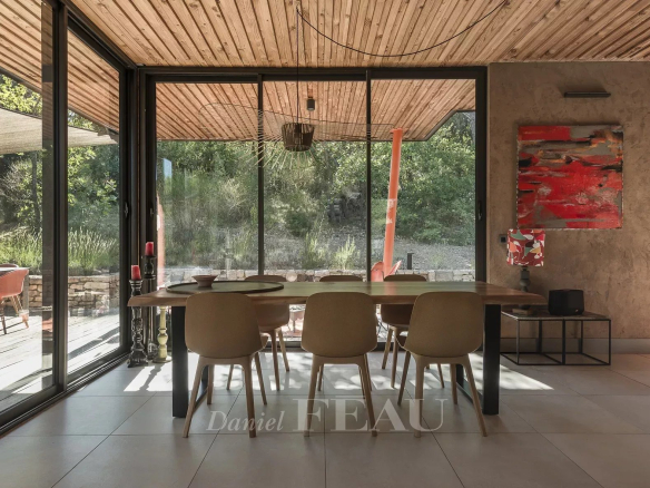Interior of an architect-designed house with a large dining table and chairs, overlooking a garden.