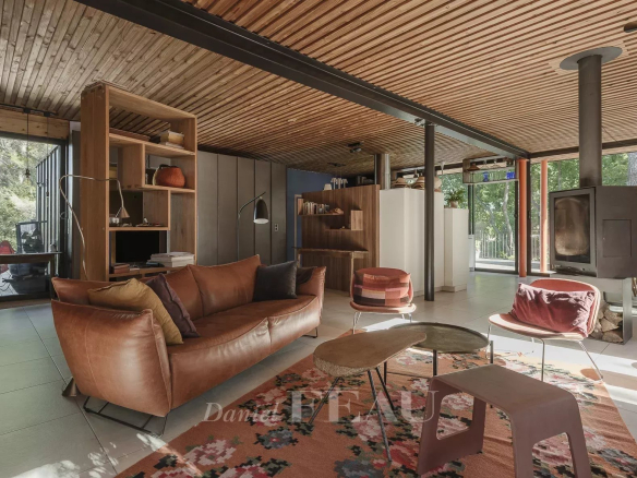 Interior of an architect-designed house with a modern living room and fireplace, surrounded by nature.
