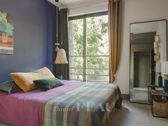 Bedroom in an architect-designed house in Aix-en-Provence, decorated with a colorful bed and a large window.