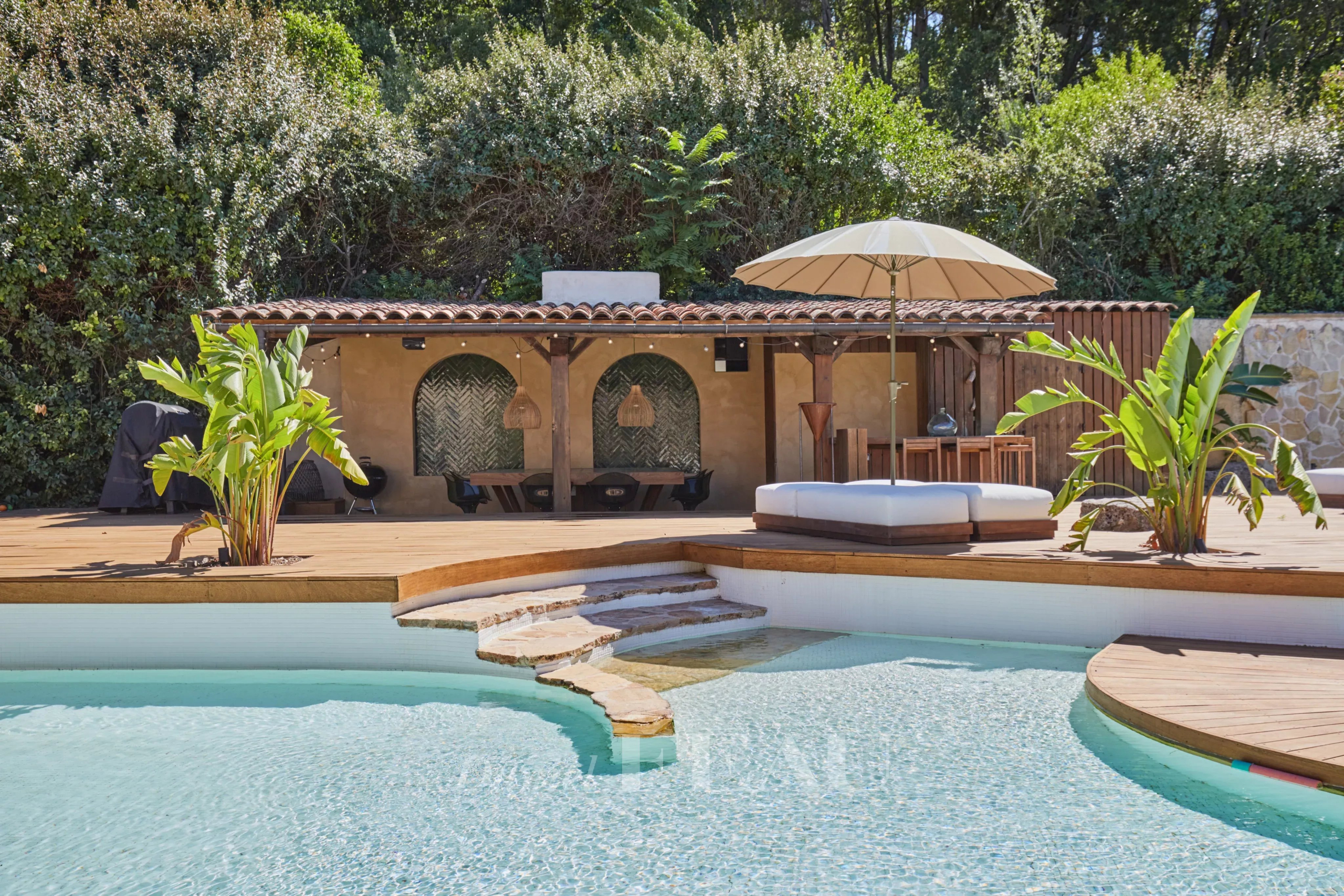 Piscine avec terrasse en bois et pool-house dans une propriété à Aix-en-Provence.