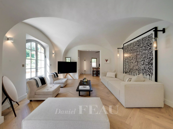 Intérieur d'un salon moderne avec des canapés clairs et des murs arrondis.