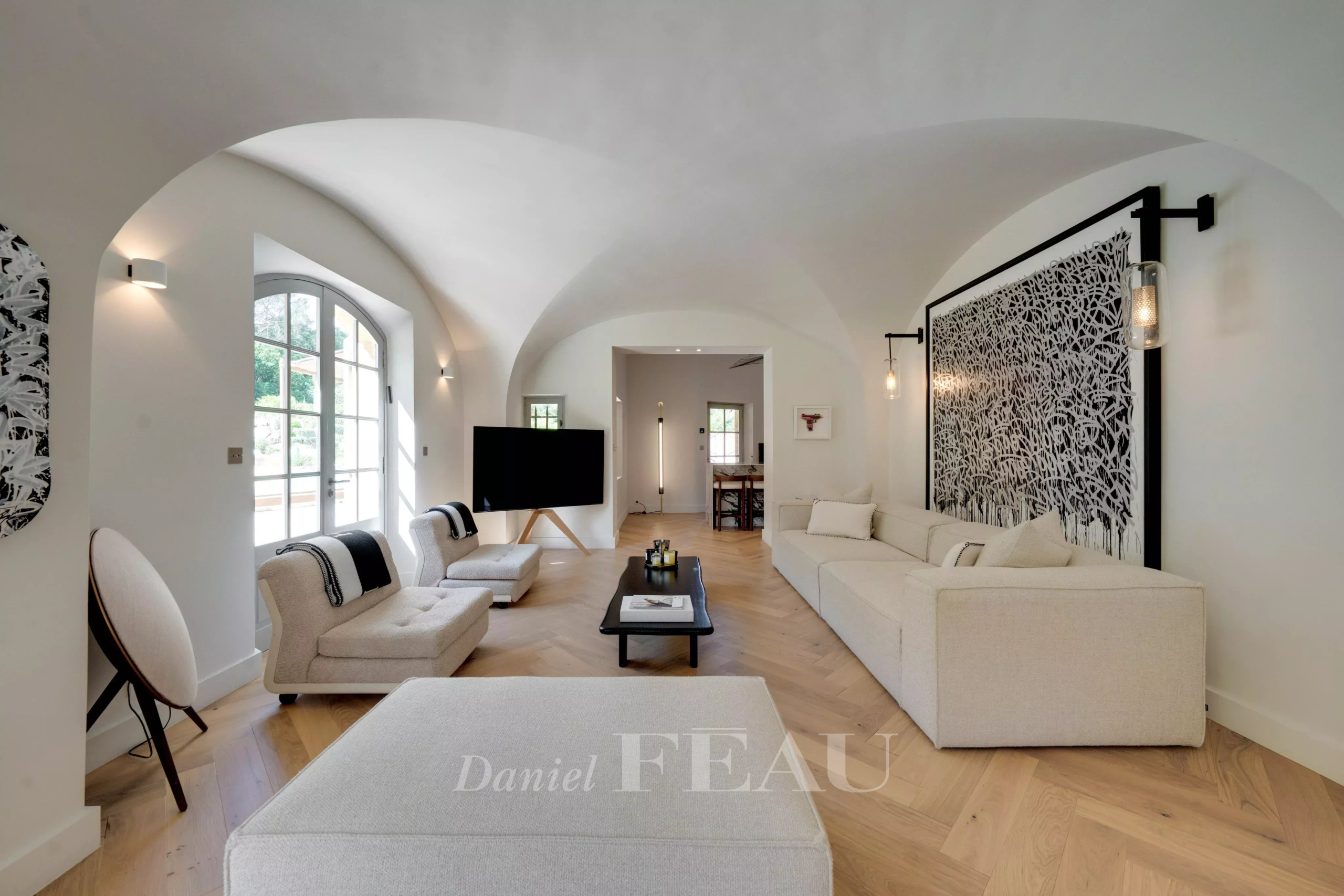 Intérieur d'un salon moderne avec des canapés clairs et des murs arrondis.