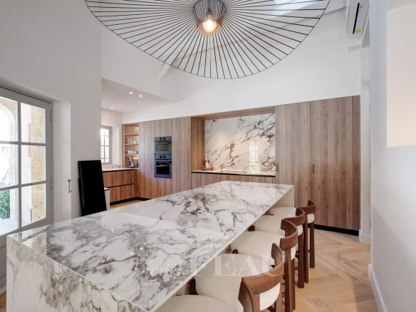 Cuisine moderne avec un grand plan de travail en marbre et des meubles en bois, éclairage design.