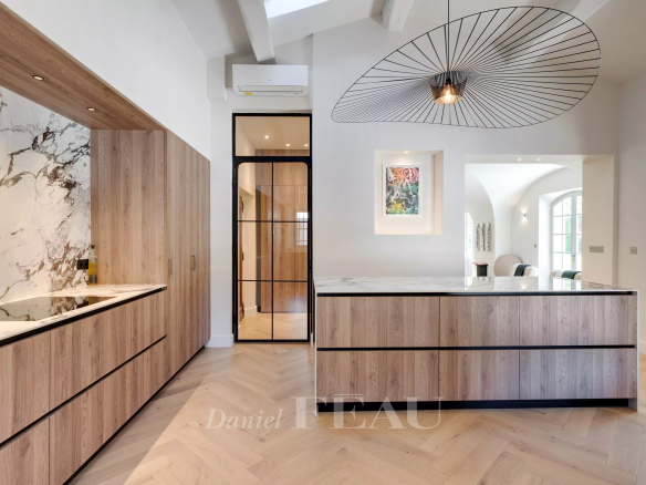 Cuisine moderne avec îlot central et éléments en bois et marbre.