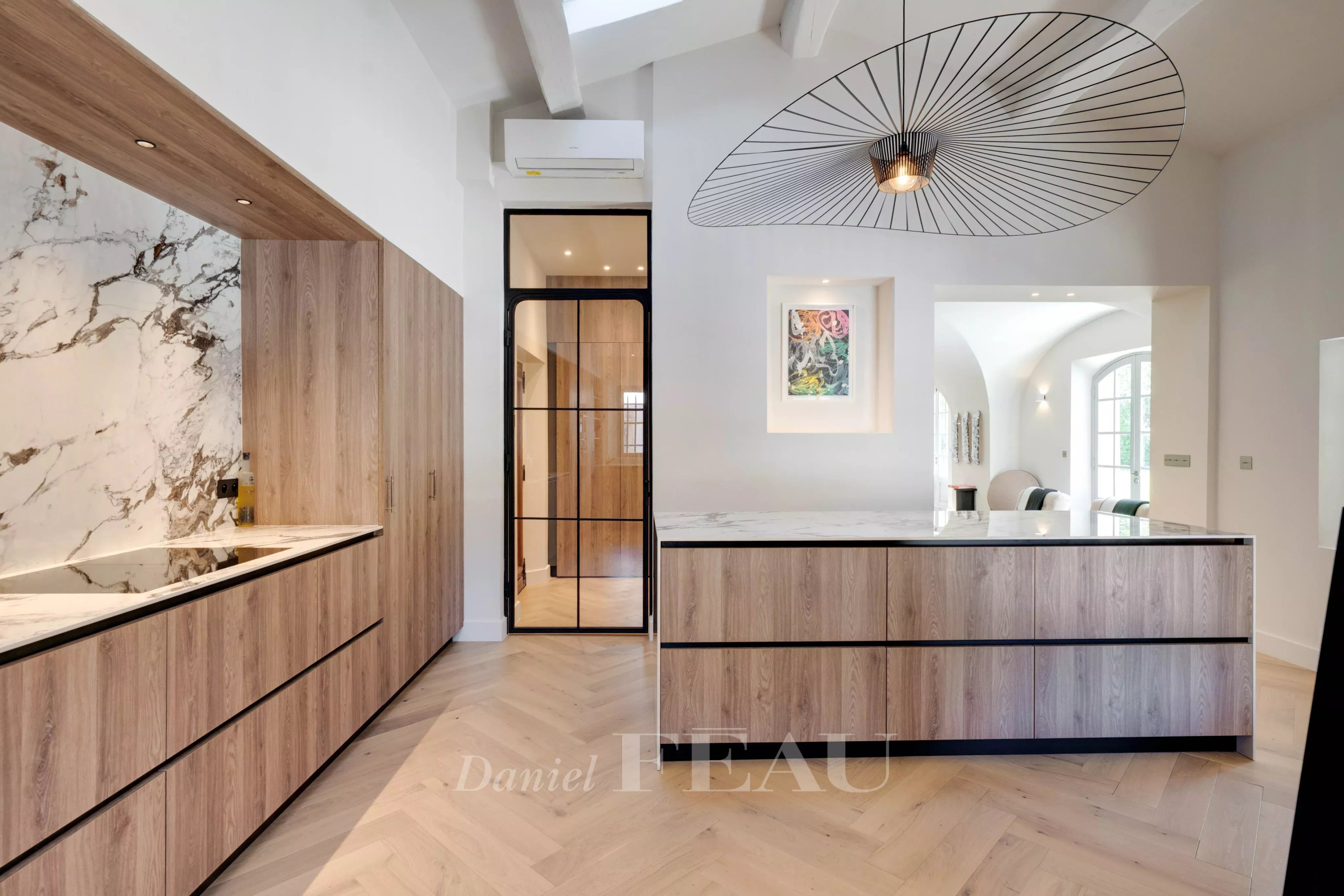 Cuisine moderne avec îlot central et éléments en bois et marbre.