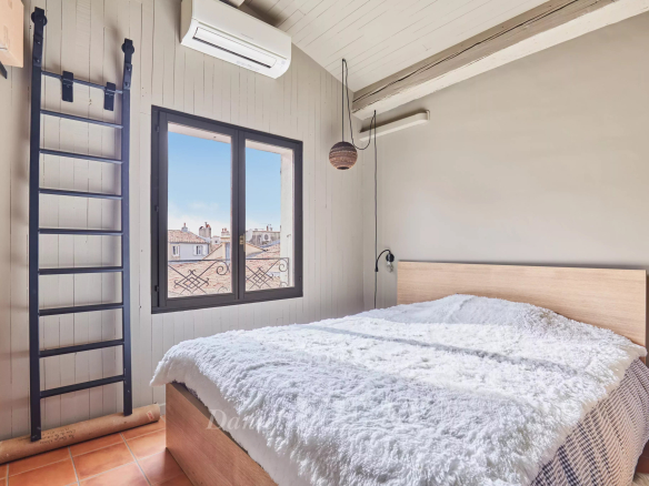 Chambre d'un loft d'architecte à Aix-en-Provence avec lit et fenêtre donnant sur le toit.