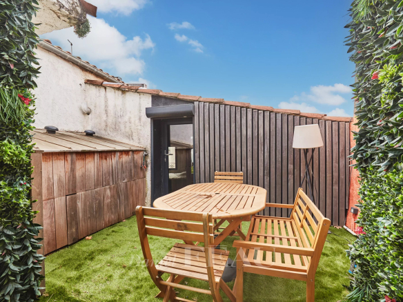 Terrasse d'un loft d'architecte à Aix-en-Provence avec mobilier en bois et verdure.