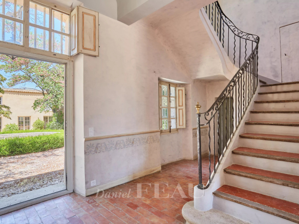 Intérieur d'une bastide du XVIIIème siècle avec un escalier et une porte donnant sur l'extérieur.