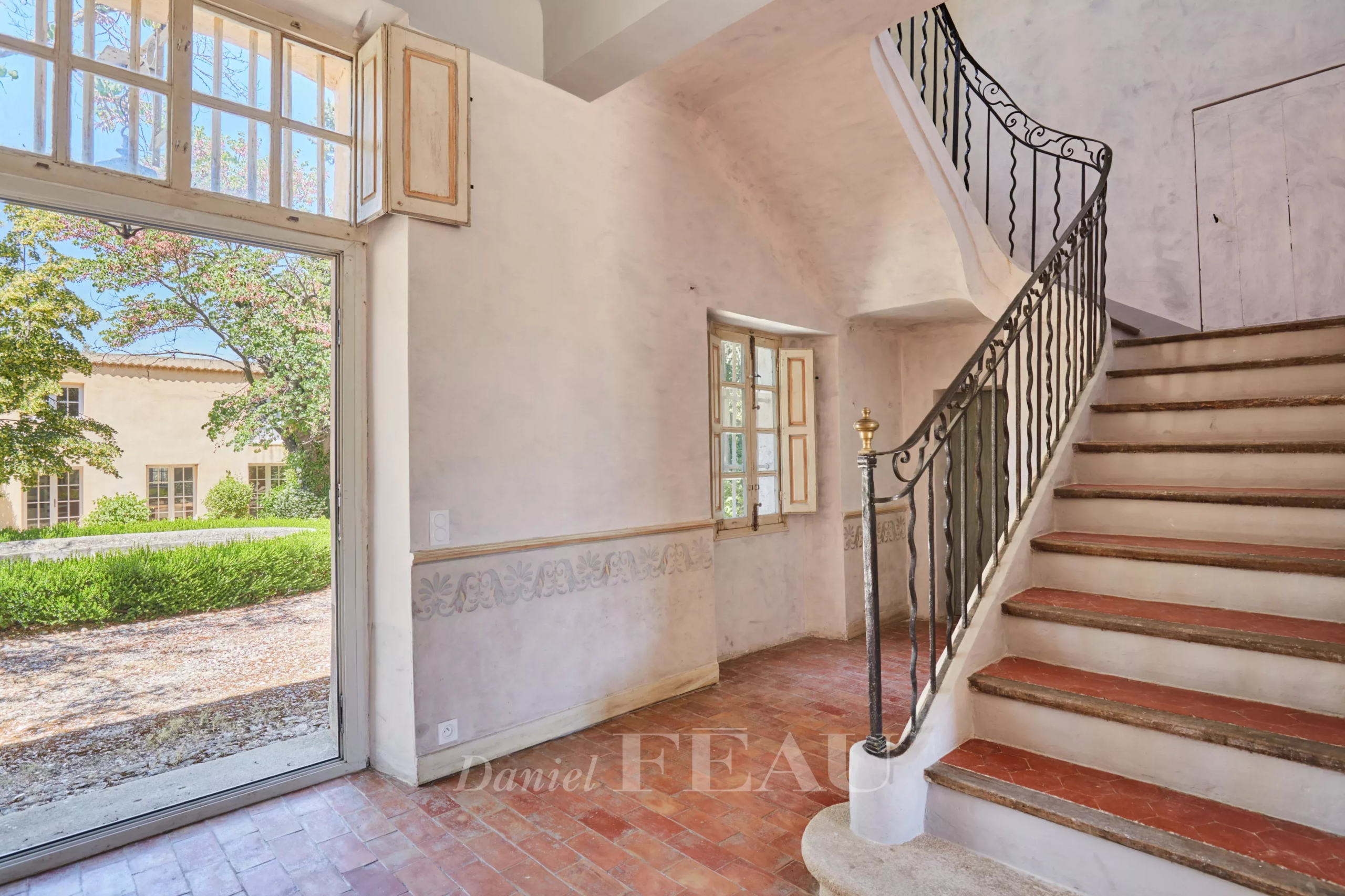 Intérieur d'une bastide du XVIIIème siècle avec un escalier et une porte donnant sur l'extérieur.