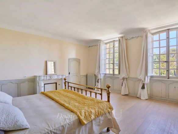 Chambre spacieuse d'une bastide du XVIIIème siècle à Aix-en-Provence, avec fenêtres et parquet clair.