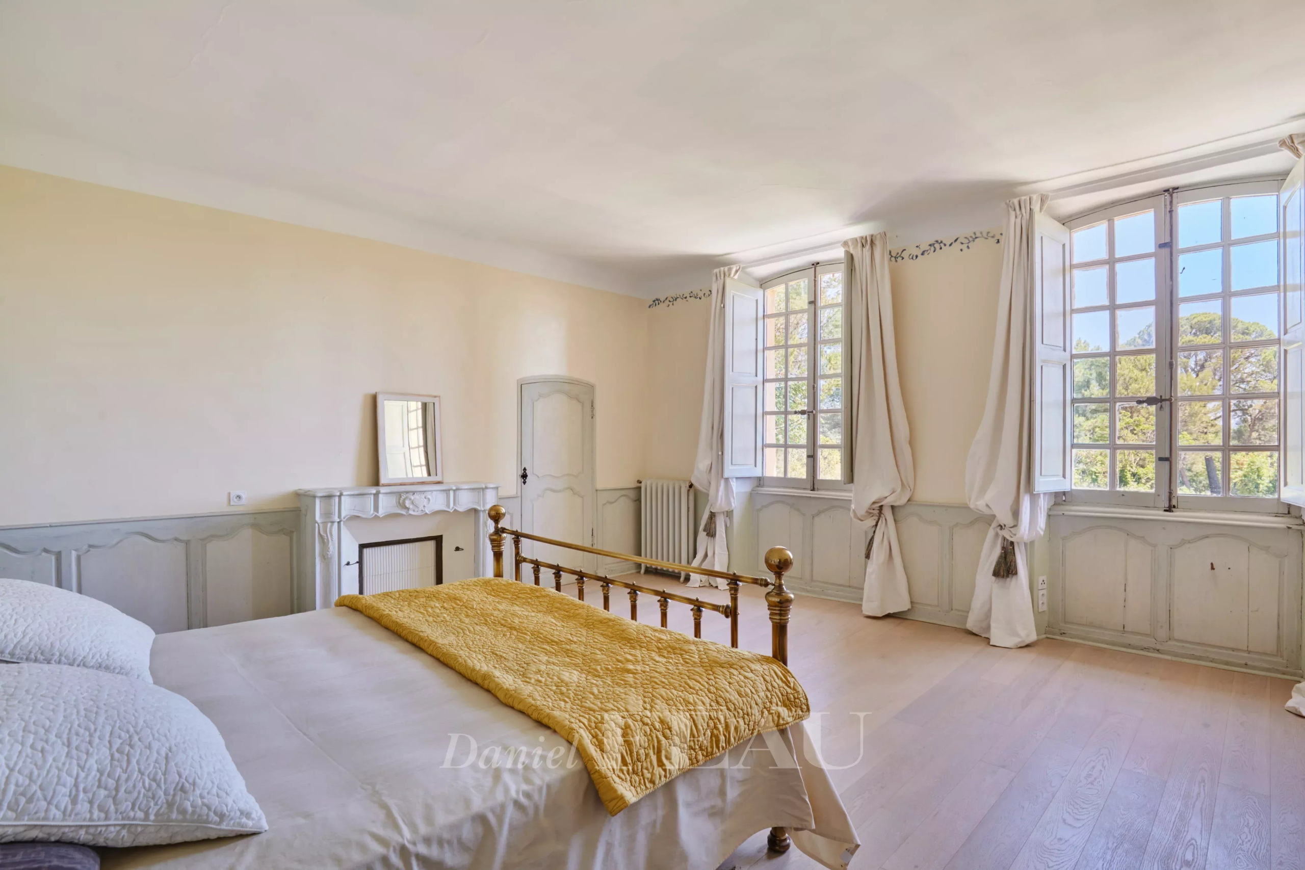 Chambre spacieuse d'une bastide du XVIIIème siècle à Aix-en-Provence, avec fenêtres et parquet clair.