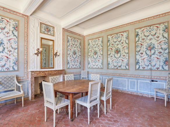Intérieur d'une bastide du XVIIIème siècle avec des murs décorés et une table ronde entourée de chaises.