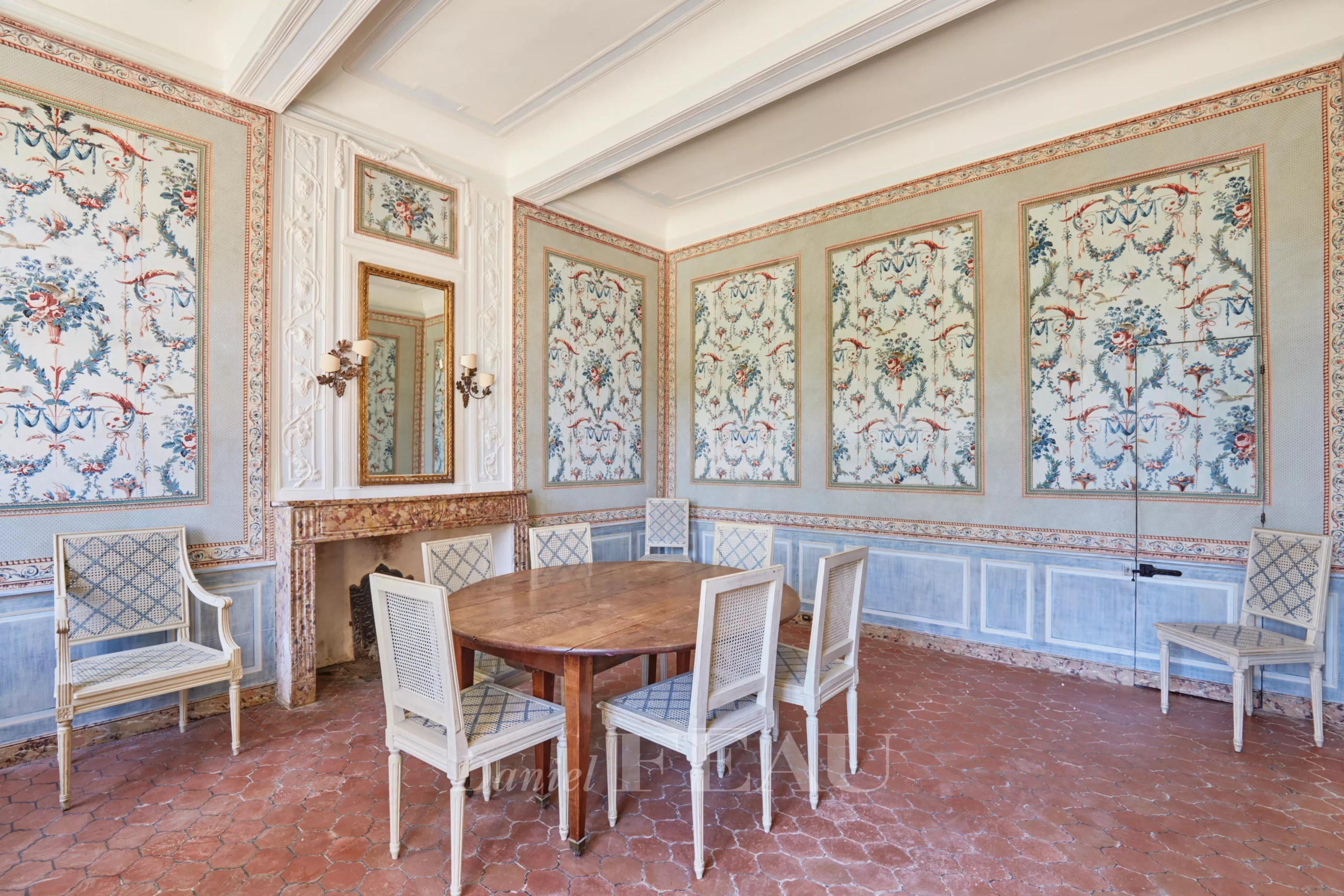 Intérieur d'une bastide du XVIIIème siècle avec des murs décorés et une table ronde entourée de chaises.