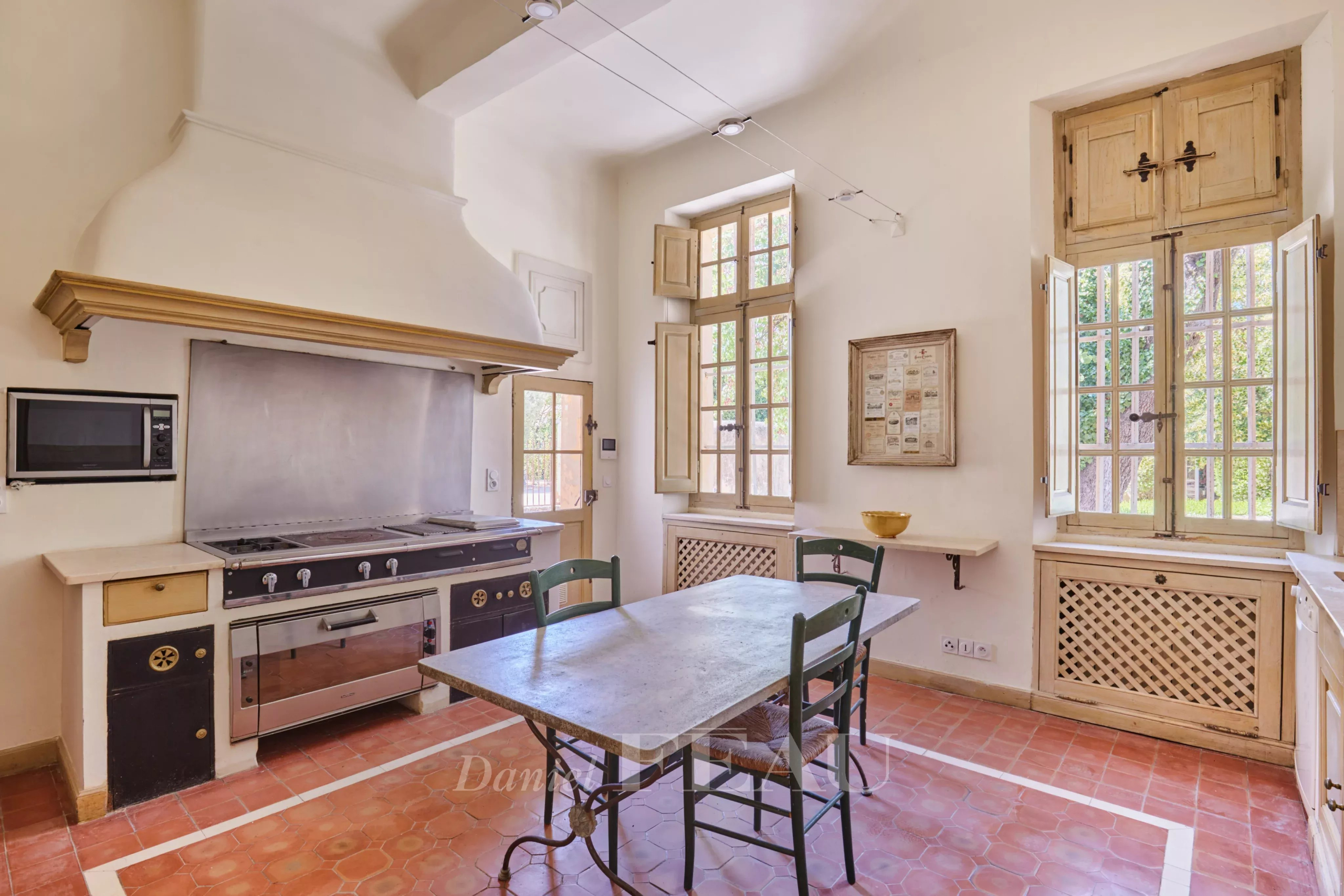Cuisine d'une bastide du XVIIIème siècle à Aix-en-Provence avec table et fenêtres lumineuses.