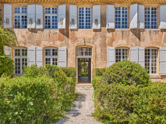 Façade d'une bastide du XVIIIème siècle avec fenêtres à volets, entourée de verdure à Aix-en-Provence.