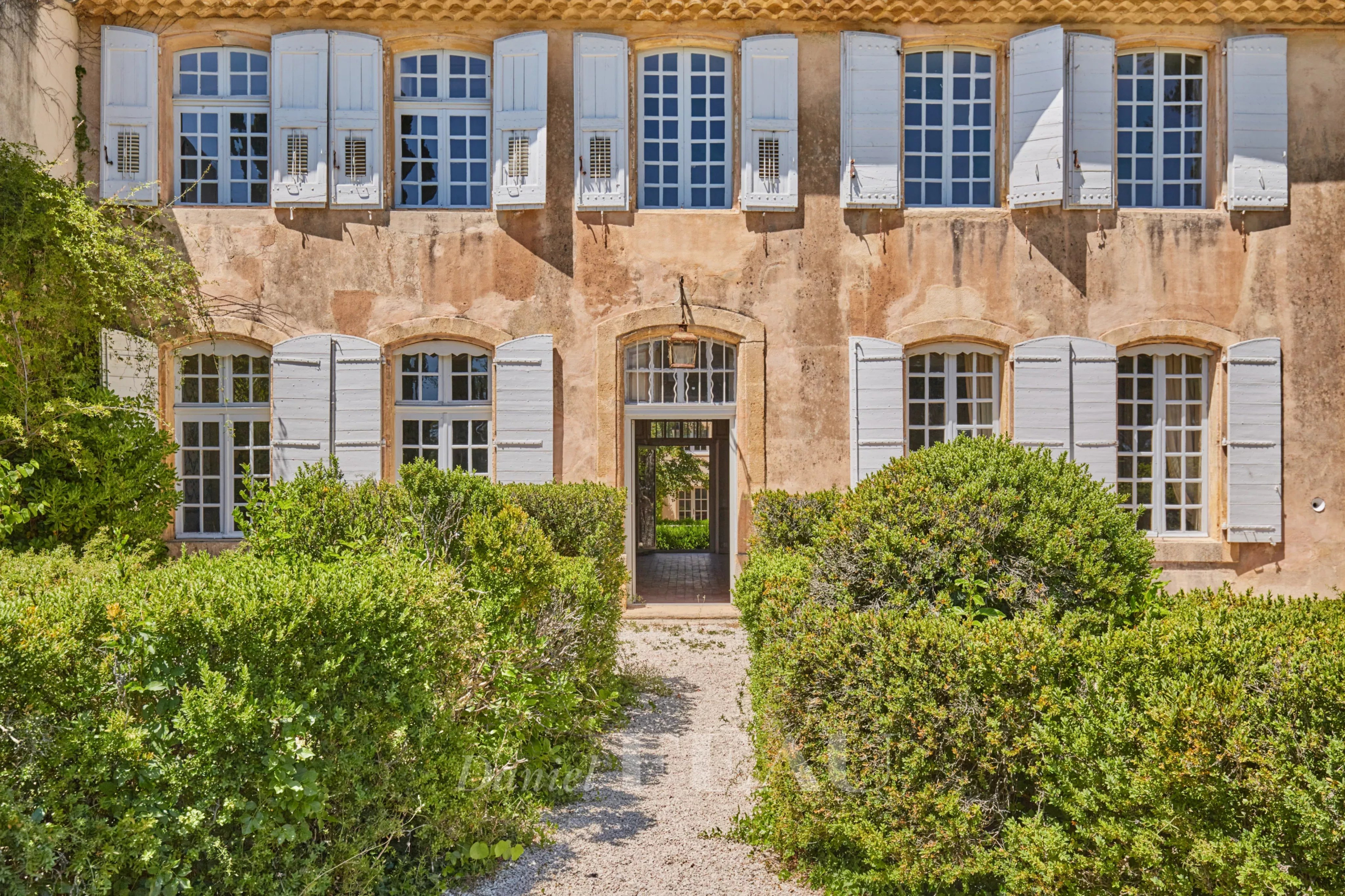 Façade d'une bastide du XVIIIème siècle avec fenêtres à volets, entourée de verdure à Aix-en-Provence.