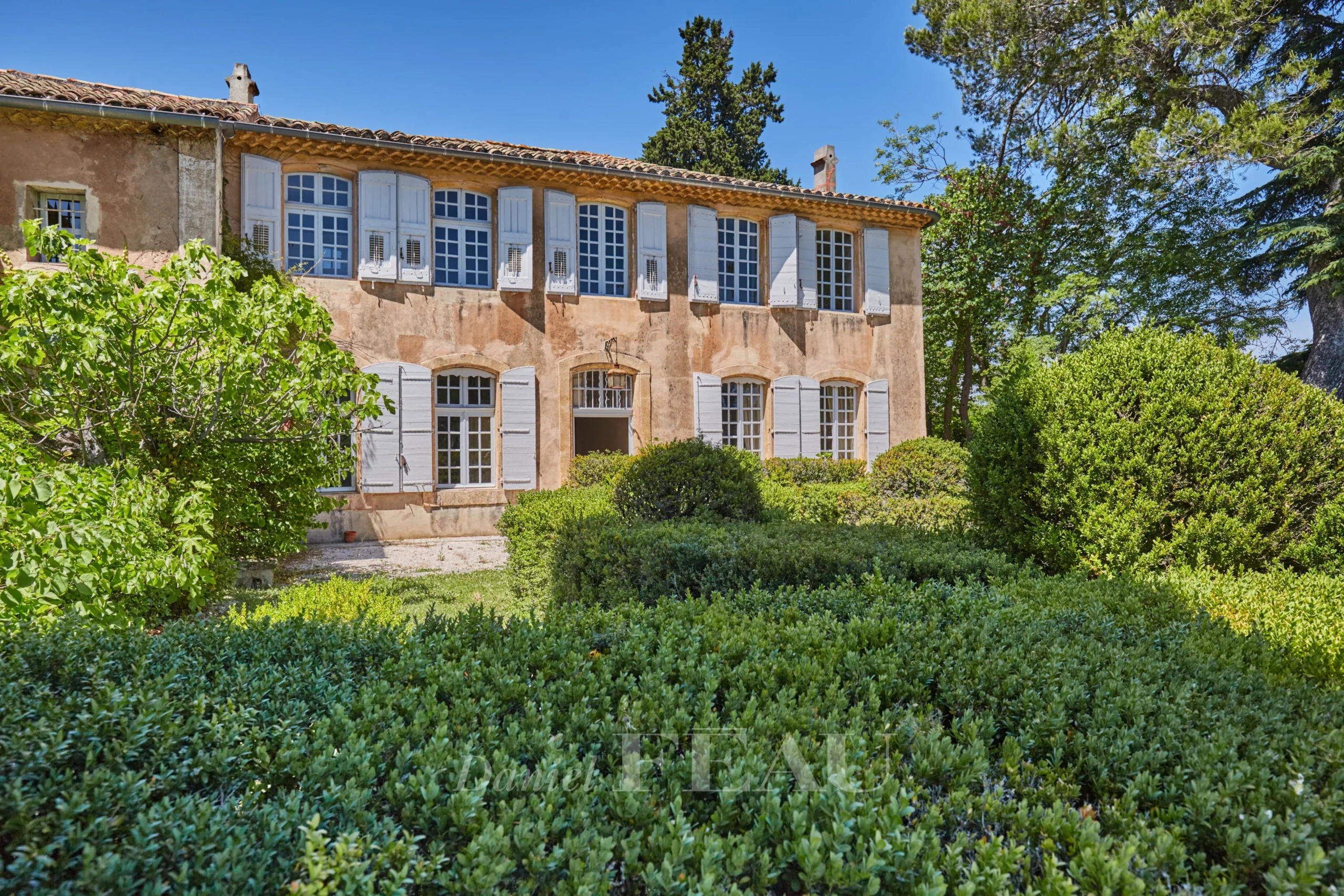 Bastide du XVIIIème siècle avec fenêtres à volets, jardin verdoyant à Aix-en-Provence.