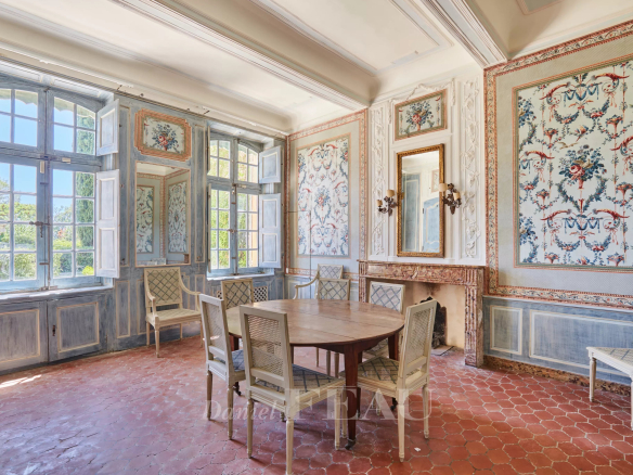 Intérieur d'une bastide du XVIIIème siècle avec des murs décorés et une grande table ronde.
